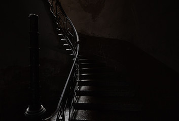 An ancient screw staircase in a dark entrance, a small ray of light illuminates the steps. - 298346597