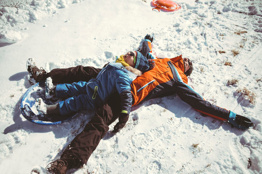 Father and son lying in snow