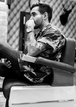 Young man with tatoo on his arm waiting in a barbershop