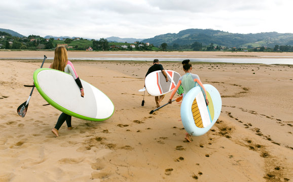 Spain, Asturias, Villaviciosa, three stand up paddler going to the water