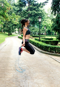 Spain, Oviedo, young woman jumping rope in the park