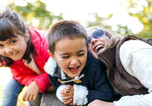 Three laughing children playing together in a park