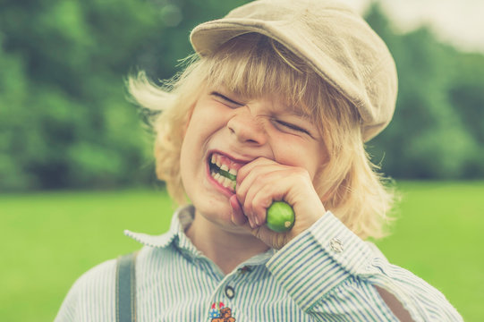 Portrait of little boy with cap eating cucumber