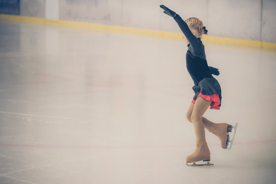 Young female, figure skater moving on ice rink at competition