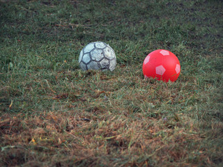 Two used balls on the grass.