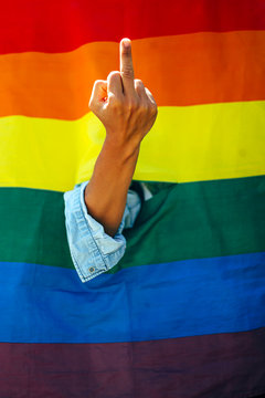 Woman giving the finger in front of a rainbow flag