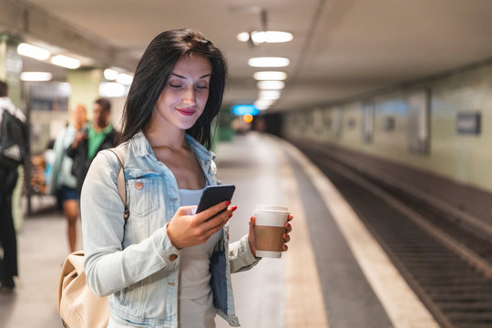 Young woman with cell phone at metro station waiting for the train, Berlin, Germany