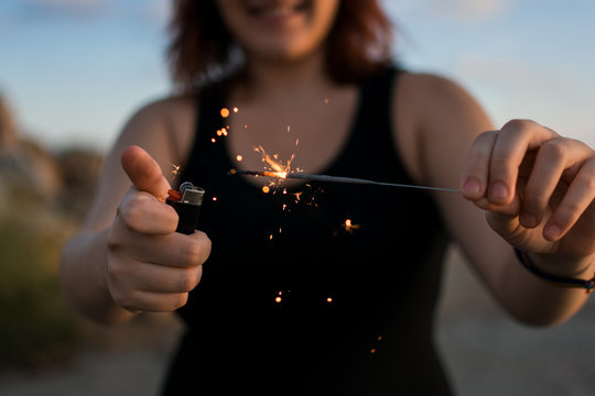 Young woman lights a sparkler with a cigarette lighter
