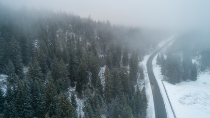 aerial view of a car traveling in winter on an asphalted road