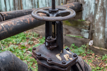 black plug valve on old water pipe at the fence
