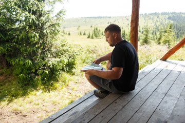 Tourist in black t-shirt sits near the house and looks at the map