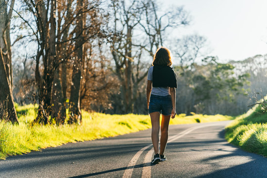 Woman walking down empty sunset road in Hawaii