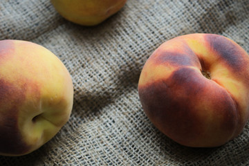 Photo of ripe peaches on a piece of fabric