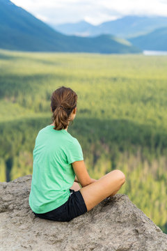 Hiker looking at green hills and lake from the edge in Washington