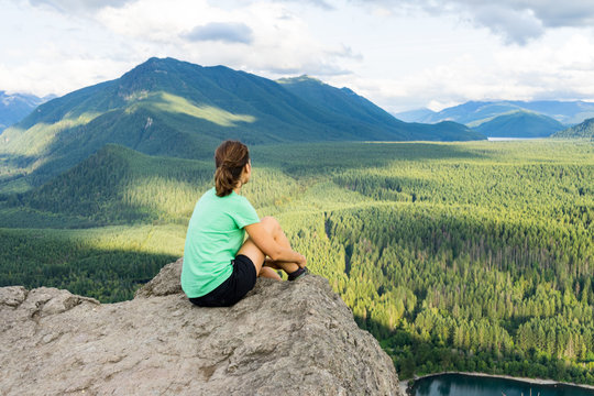 Hiker looking at green hills and lake from the edge in Washington