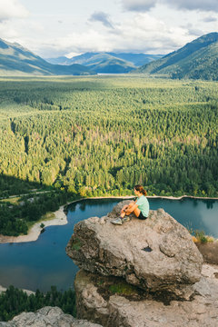 Hiker looking at green hills and lake from the edge in Washington