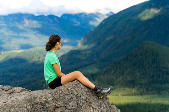 Hiker looking at green hills and lake from the edge in Washington