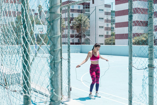 Colorful image of female athlete skipping with jumping rope on court