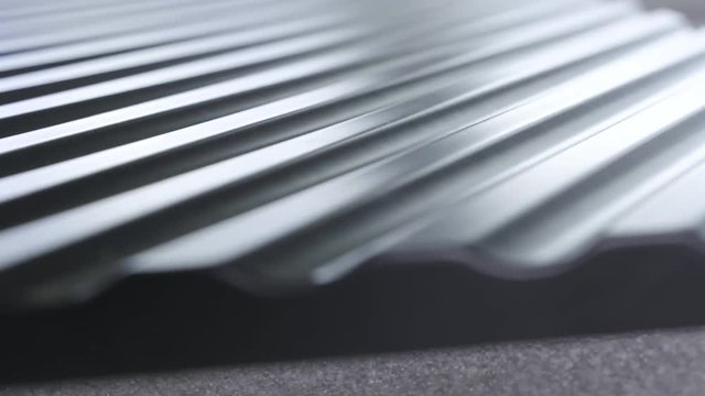 Close up side of black wavy roof tiles on blurred background. Action. Black wavy roofing material, constructional materials.