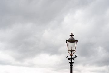 Fototapeta na wymiar Street lantern, top. Against the background of heavy autumn gray sky with gray rain clouds. Horizontal orientation.