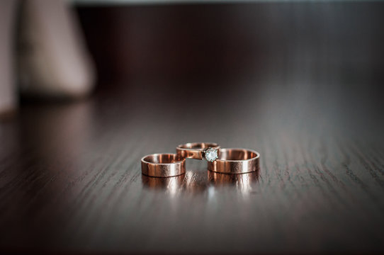 Three Gold Wedding Rings On The Table