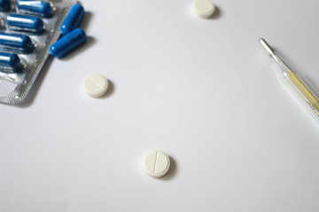 Pills and thermometer on a white background