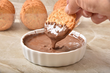 Dunking a coconut macaroon in chocolate