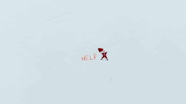 Santa Claus is making a snow angel near a mayday signal