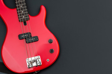 Fototapeta na wymiar Red electric bass guitar on black. Space for text.