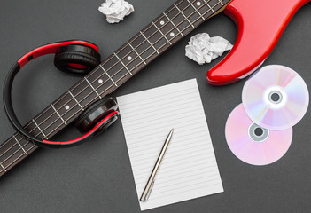 Fototapeta premium Blank notepad with electric guitar and headphones on black. Creating music.