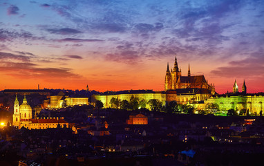 Evening view at Prague Castle Prague, Czech Republic. Nighttime panorama old town with broach tower and illuminated houses. Picturesque sunset with pink sky over skyline.