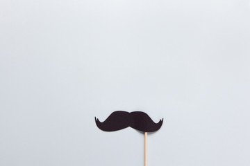 Accessory in form of black moustache on stick on grey background with place for text. Concept men's...