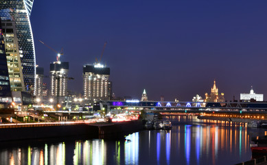 brightly lit tall buildings at night and reflected in the river