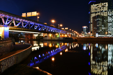 brightly lit tall buildings at night and reflected in the river