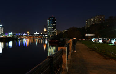 Fototapeta premium brightly lit tall buildings at night and reflected in the river