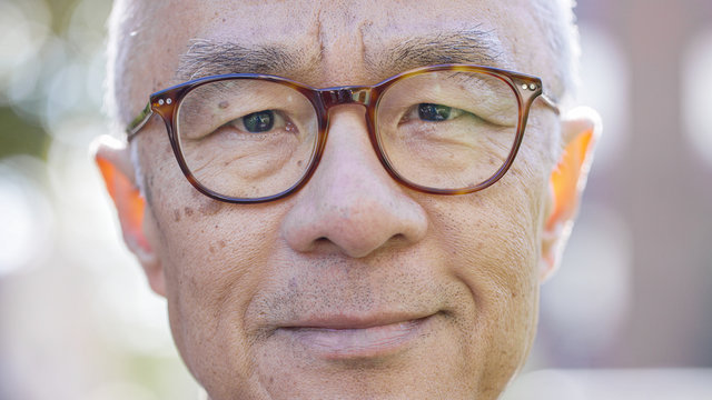 Portrait of senior Asian male wearing glasses looking to camera with a positive expression