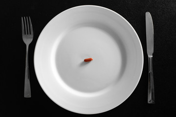 A small tablet in a plate. Medical concept. Eat pills instead of food.