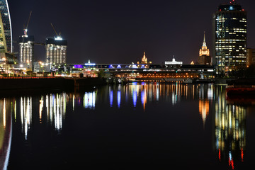 Fototapeta na wymiar brightly lit tall buildings at night and reflected in the river