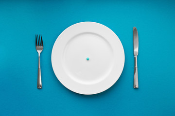A small tablet in a plate. Medical concept. Eat pills instead of food.