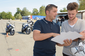 motorbike teacher showing student how to pass exam