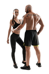Fototapeta premium Athletic man in black shorts and sneakers with brunette woman in leggings and top posing isolated on white background. Fitness couple, gym concept.