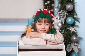 Merry Christmas, happy holidays! New Year 2020. Happy little girl in christmas elf costume with cookies in hands. A child holds a gingerbread man for Santa Claus. Portrait of a cheerful elf in a hat.