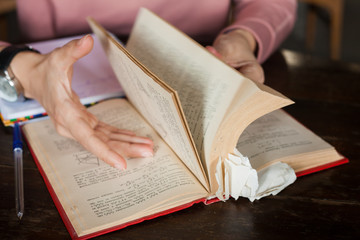 Female hands with neat manicure and a large clock leaf through a thick book with many bookmarks...