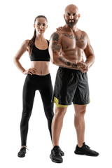 Athletic man in black shorts and sneakers with brunette woman in leggings and top posing isolated on white background. Fitness couple, gym concept.