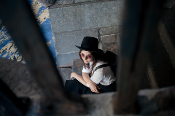 young woman in a hat and with a backpack walks in the city and uses a smartphone.