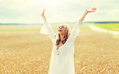 country, nature, summer holidays, vacation and people concept - smiling young woman in white dress on cereal field