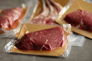 Raw meat vacuum-packed,  steaks on a wooden board.