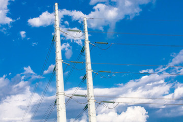 A low angle view of twin electric poles supporting medium voltage wires with insulators and access...