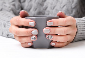 Woman's hands with geometric manicure nail design in cozy sweater