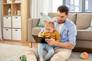 family, fatherhood and technology concept - happy father and baby daughter with tablet pc computer at home